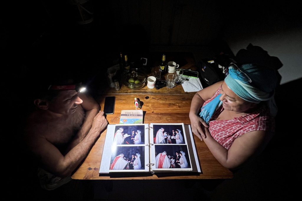 Marlen Arévalo y Édgar Cruz miran el álbum de fotos de su matrimonio a la luz de una linterna, durante un apagón en su casa en el departamento del Meta. Foto: Natalia Pedraza Bravo.
