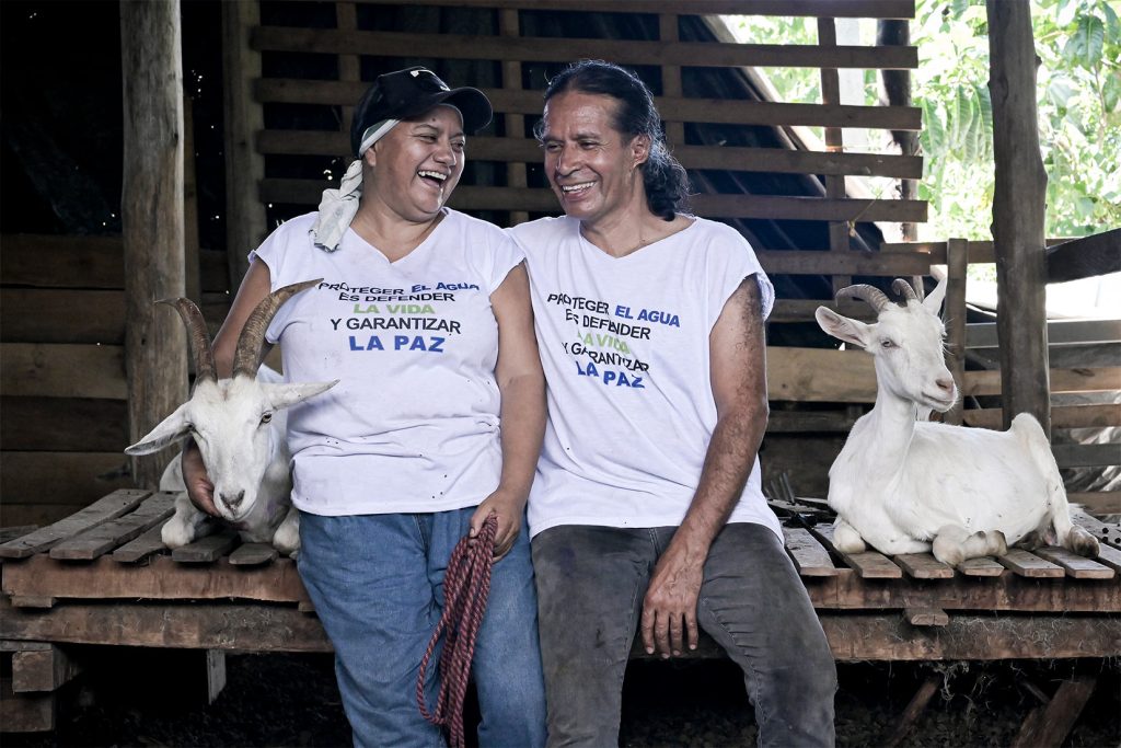 Marlén Arévalo y Édgar Cruz junto a sus cabras en el departamento del Meta, vistiendo camisetas de Cropohumadea con un mensaje en defensa del agua. Foto: Natalia Pedraza Bravo.